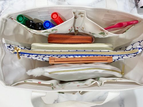 ワイルドストロベリー柄のトートバッグに文房具を入れているところ