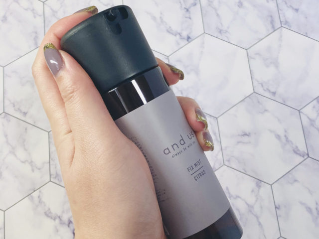 噴射口を上に向けた状態のフィックスミストを手に持っている