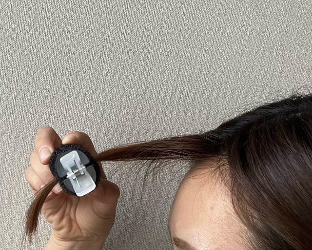 ダイソーの前髪カーラーに前髪を挟んでいる