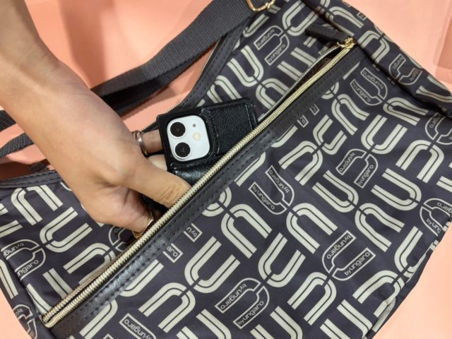 ユー バイ ウンガロ 7 Pockets 軽量ショルダーバッグの外ポケットにスマホを入れているところ