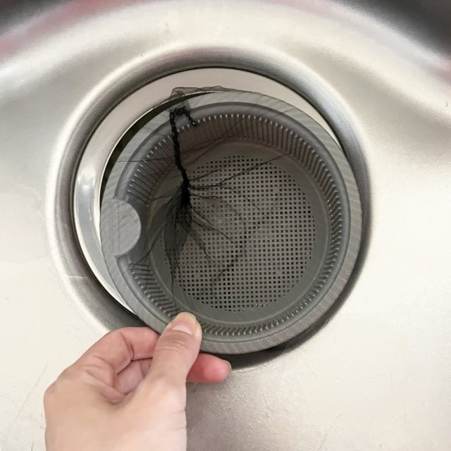 排水溝ネットを手で持って設置している写真