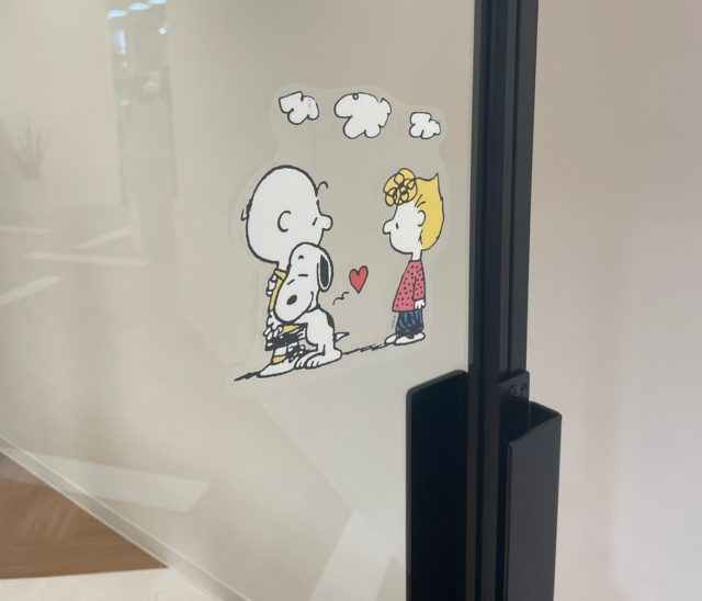 スヌーピーがチャーリーブラウンに甘えているステッカーをアクリル板に貼ったところ
