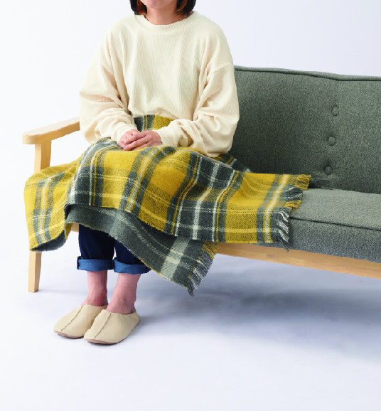 リバーシブルポンチョストール、イエローを膝掛けしている画像