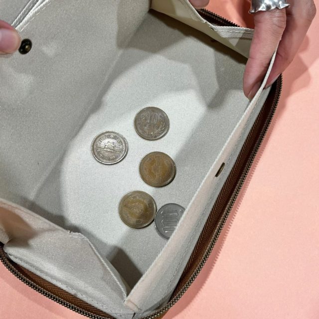 財布の中のコインケースに小銭を入れている