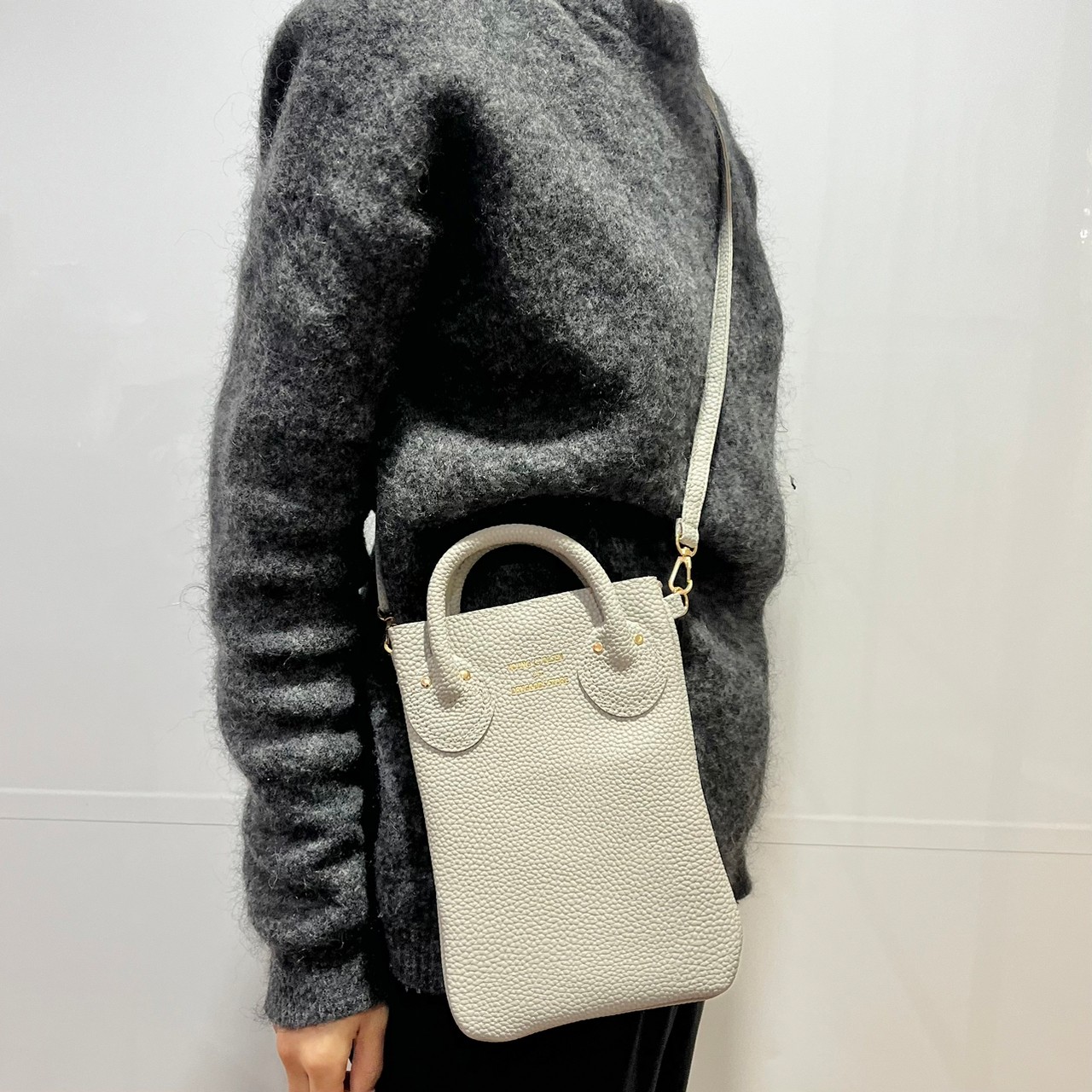 スマホショルダーバッグ、ベージュを肩掛けしている