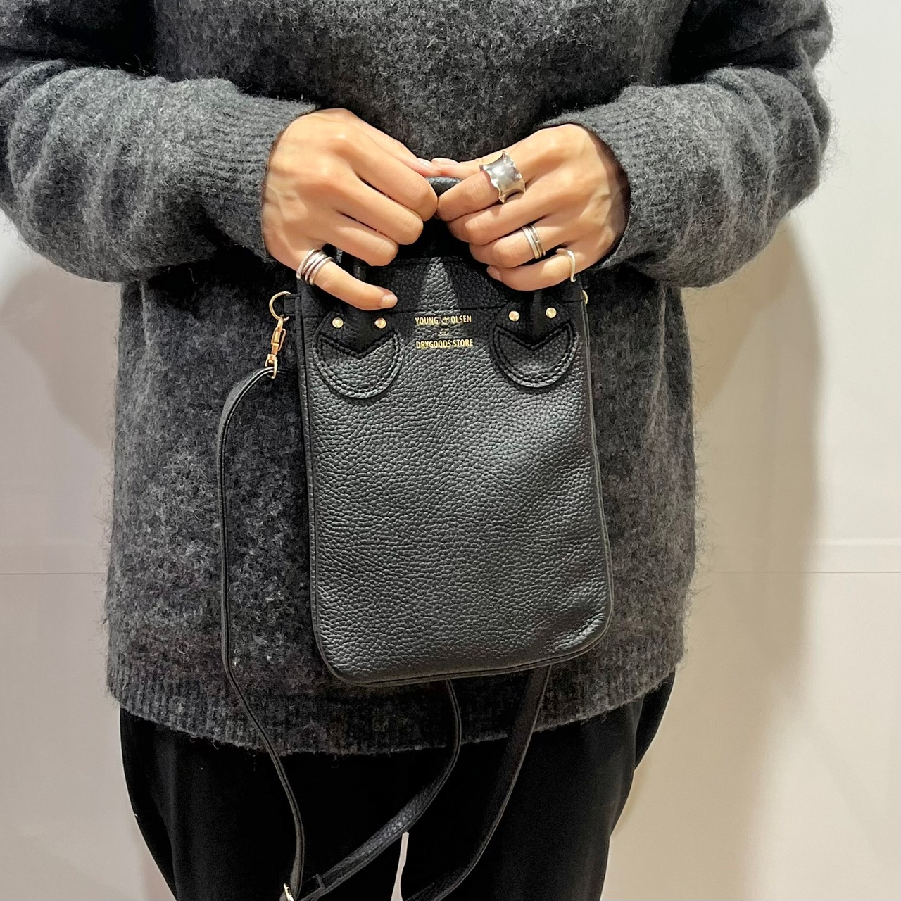 スマホショルダーバッグ、ブラックを手に持っている